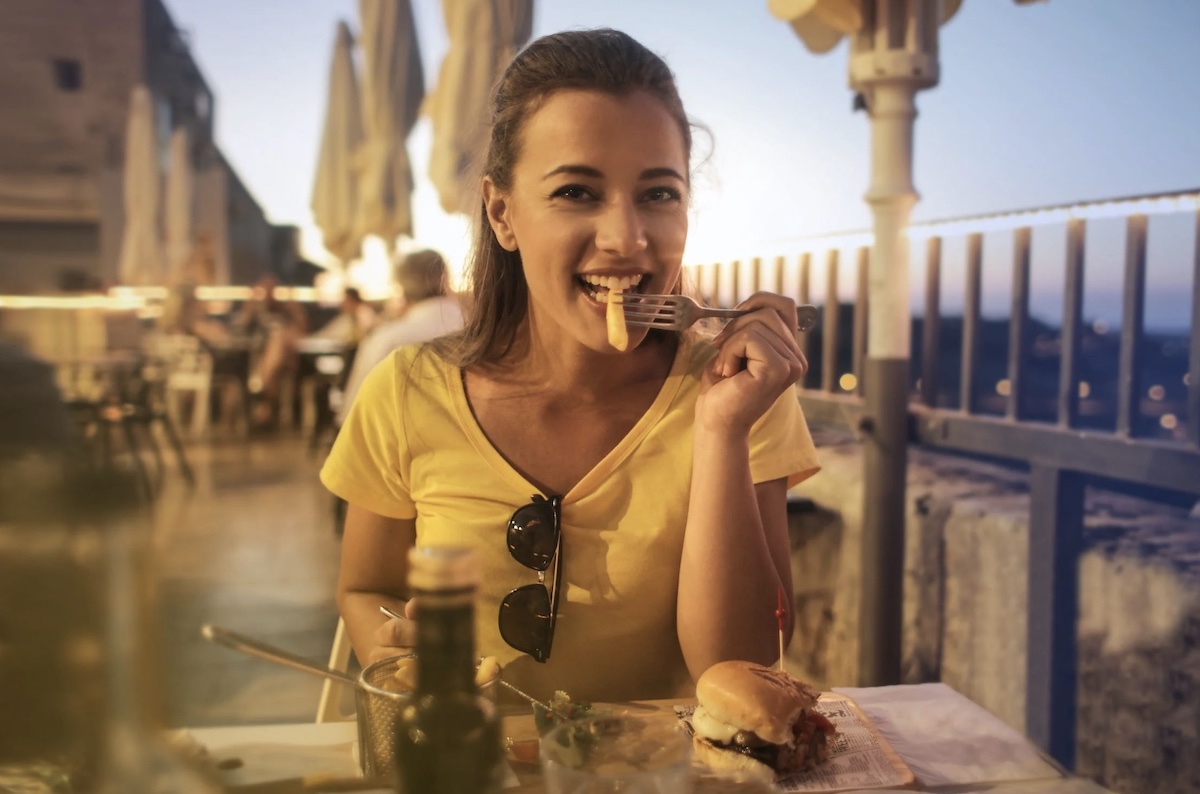 Woman eating fries outside. Image: Pexels - Andrea Piacquadio