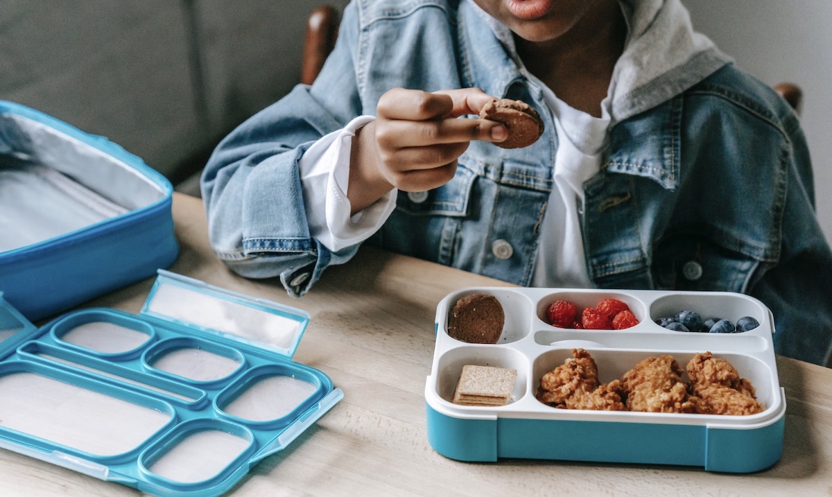 Child eating a snack from lunchbox. Image: Pexels - Katerina Holmes