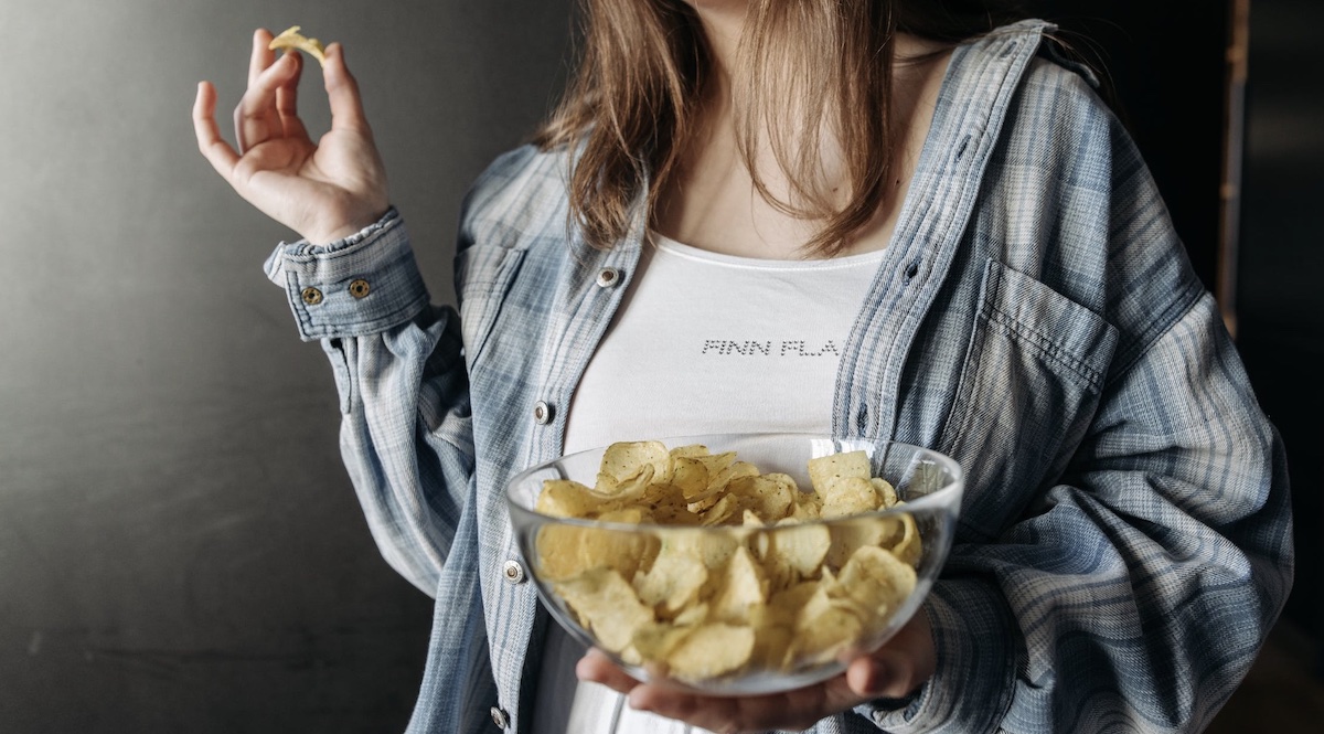 Woman eating a bag of chips from a bowl