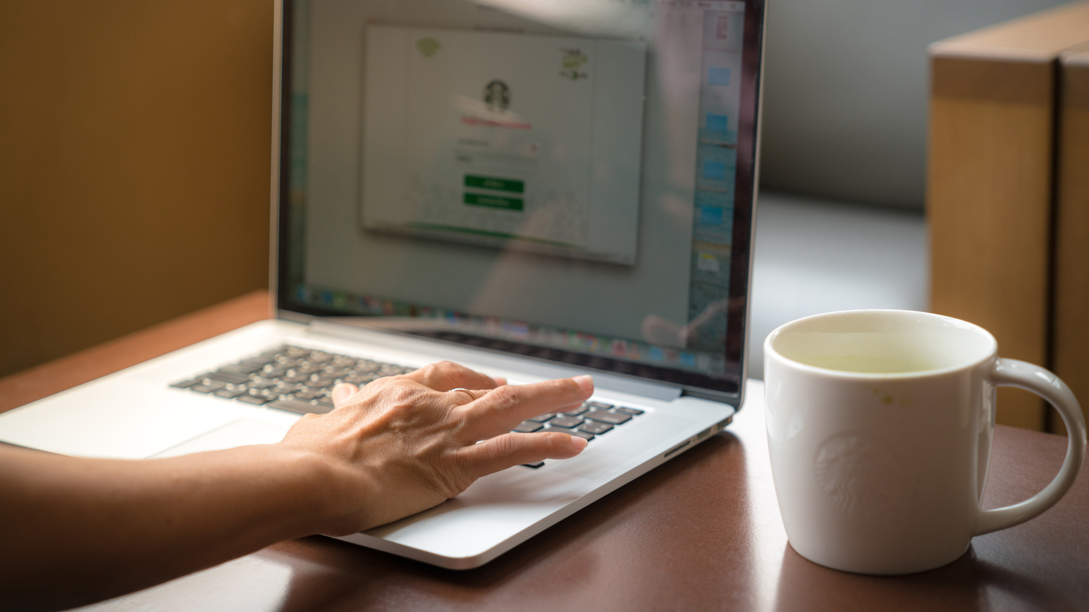 woman working at laptop with venti starbucks coffee 