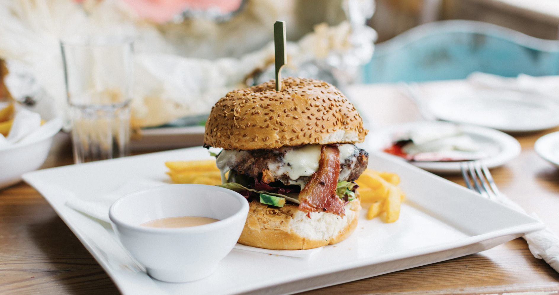 A juicy hamburger with bacon and avocado and fries on a plate