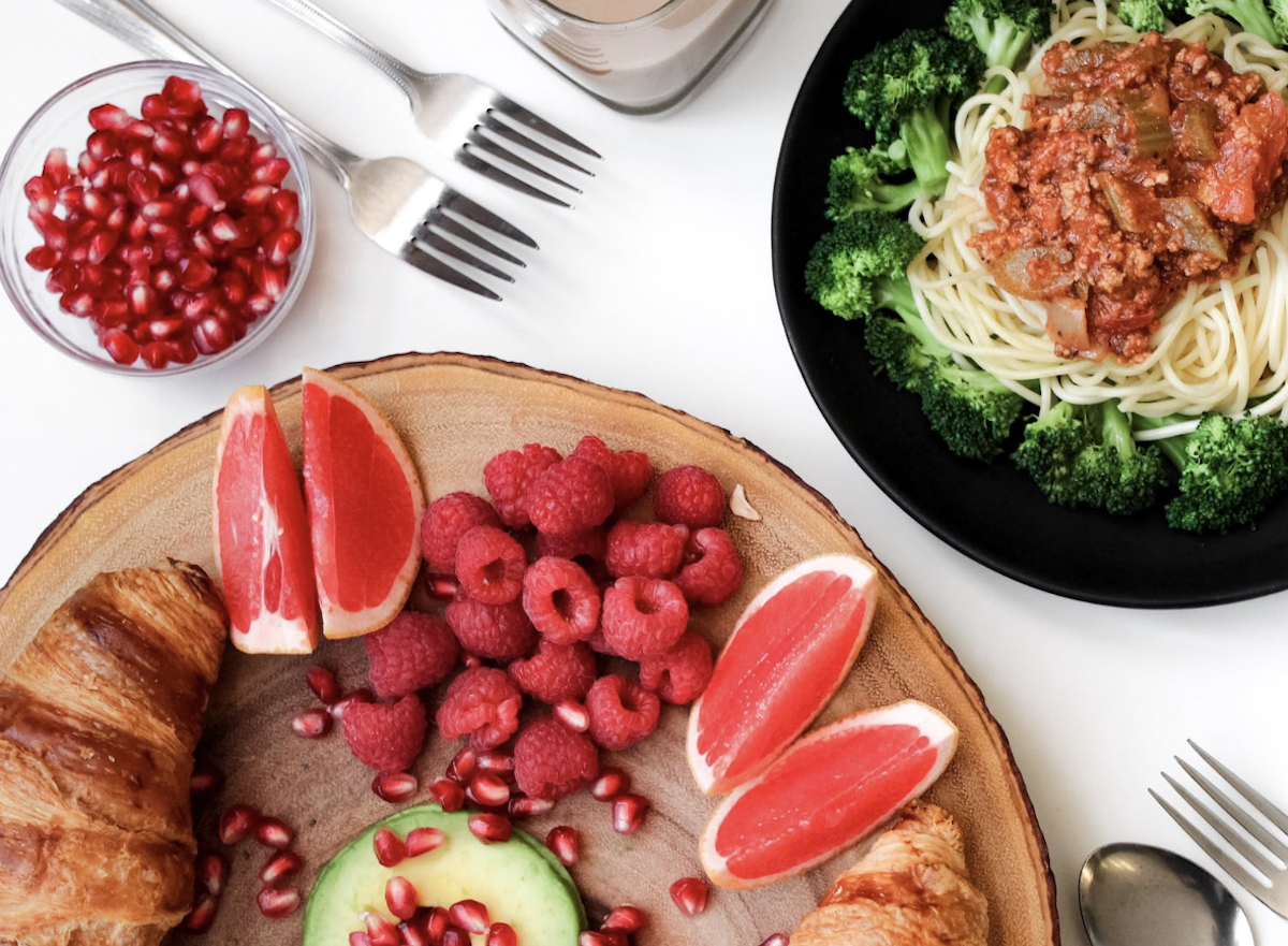 Plate with fruits and a bowl with broccoli and spaghetti.