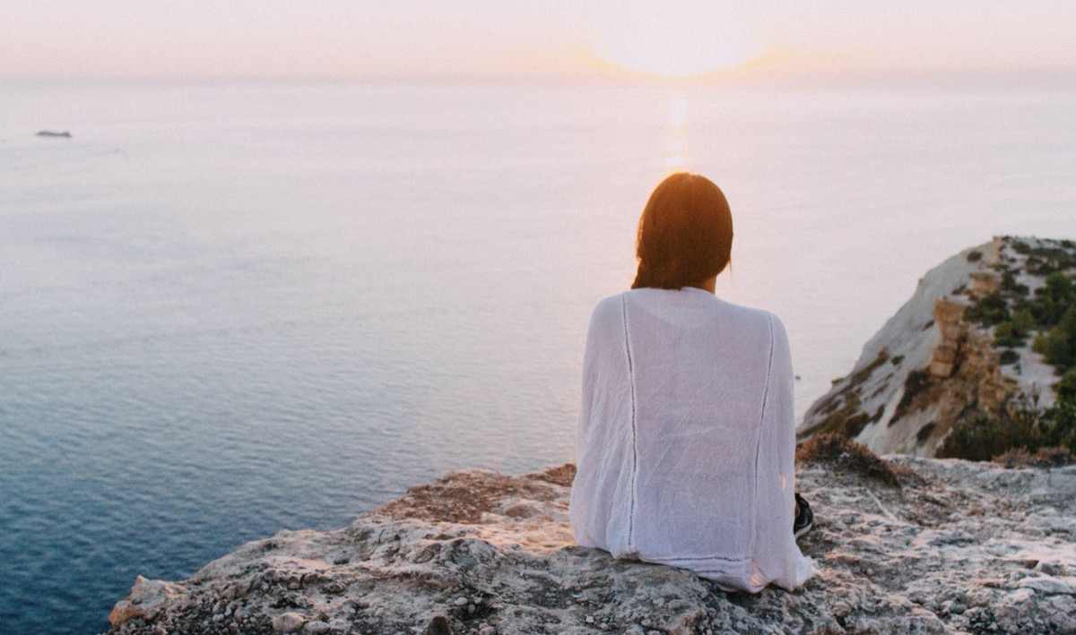 Woman sitting outside by the ocean. Image: Pexels - Riccardo