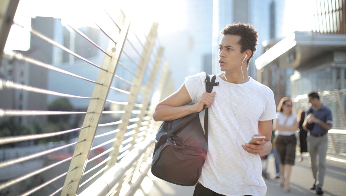 Man with gym bag in the morning listening to music 