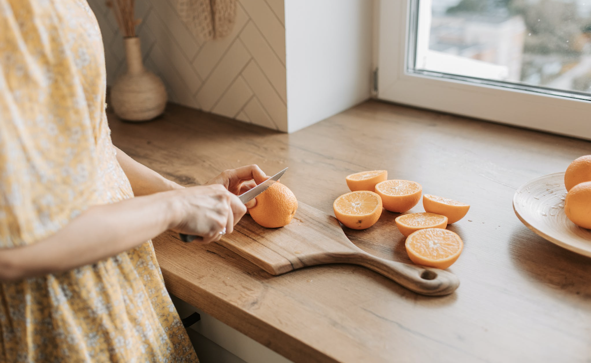 Slicing oranges on cutting board.