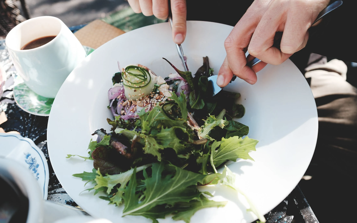 Person eating a salad full of greens.