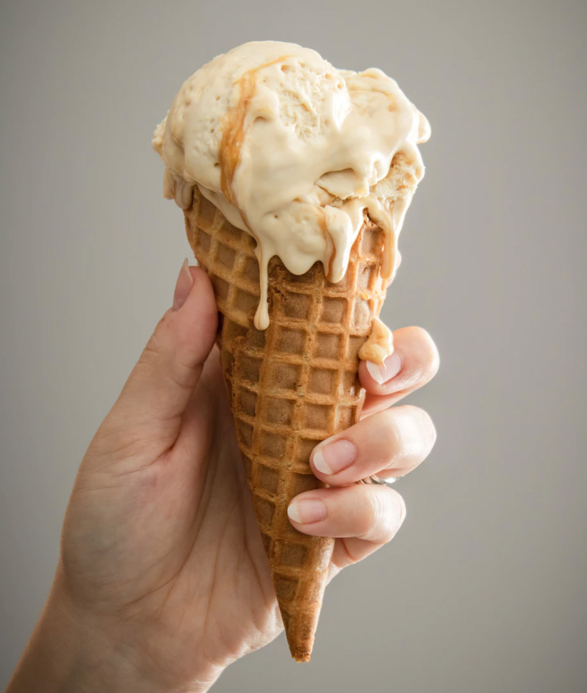 Hand holding an ice cream cone and ice cream.