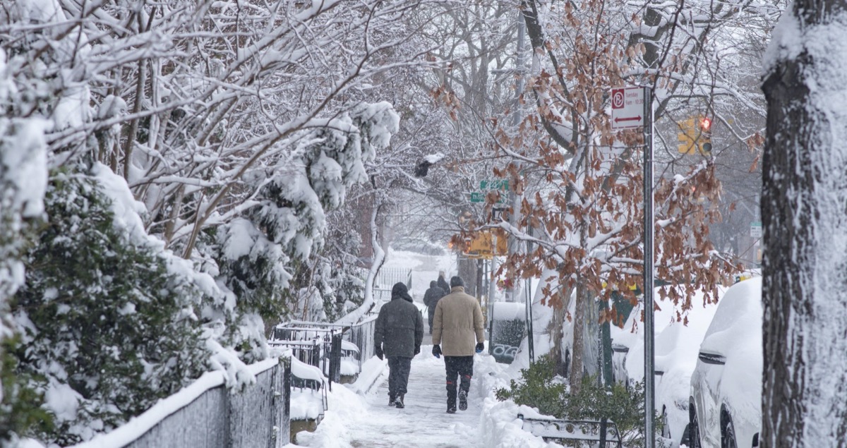 Snowy sidewalk people walking.