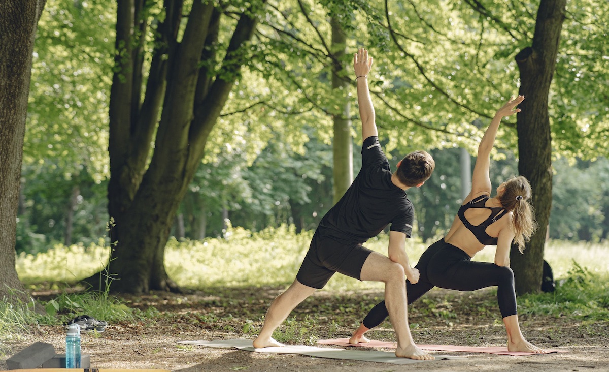 Man and woman doing yoga in park. Image: Pexels - Gustavo Fring
